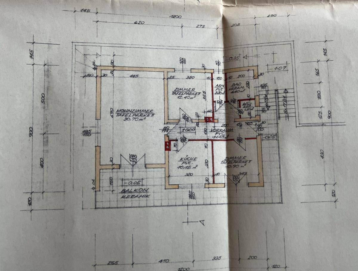 Grundriss des Erdgeschosses mit Wohnzimmer, Küche und Balkonzugang.