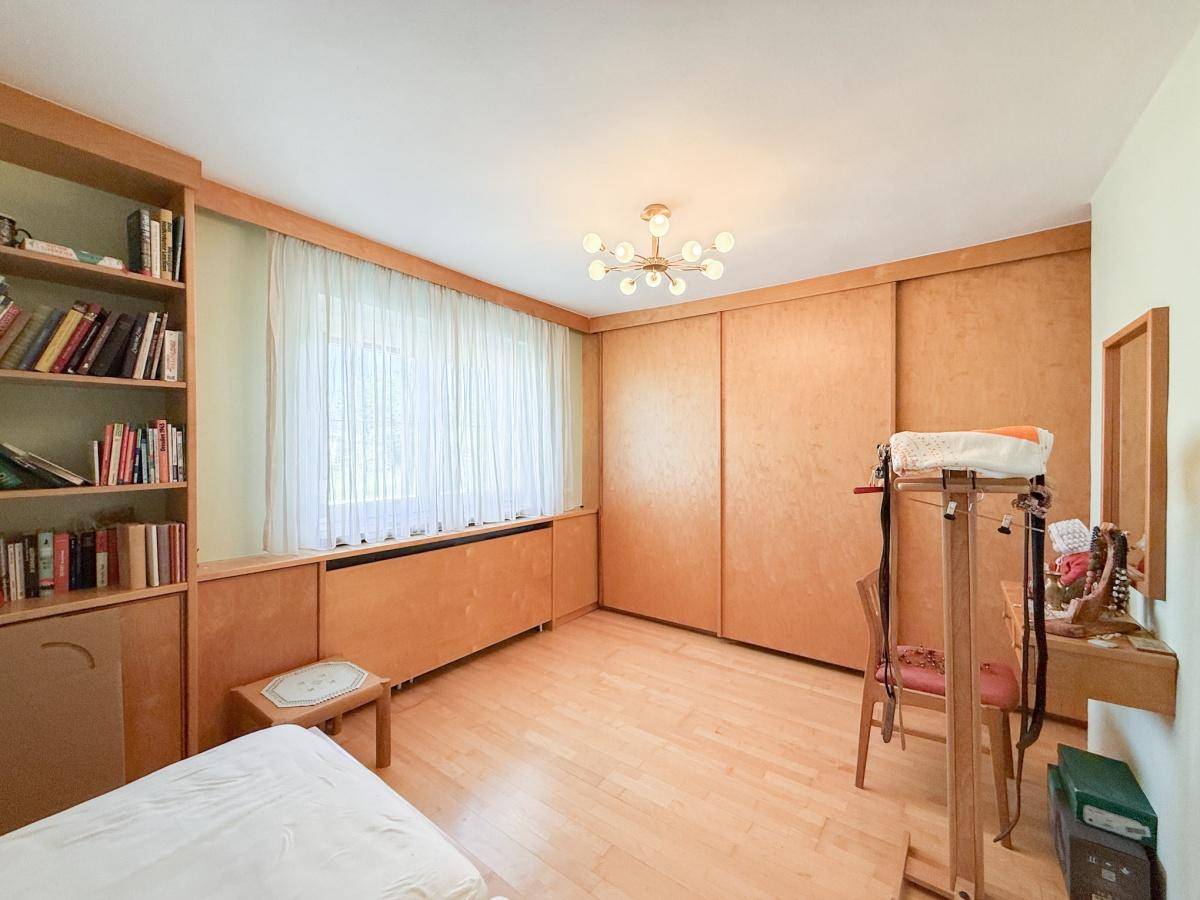 Helles Zimmer mit maßgefertigten Holzregalen, Schreibtisch und großem Fenster.