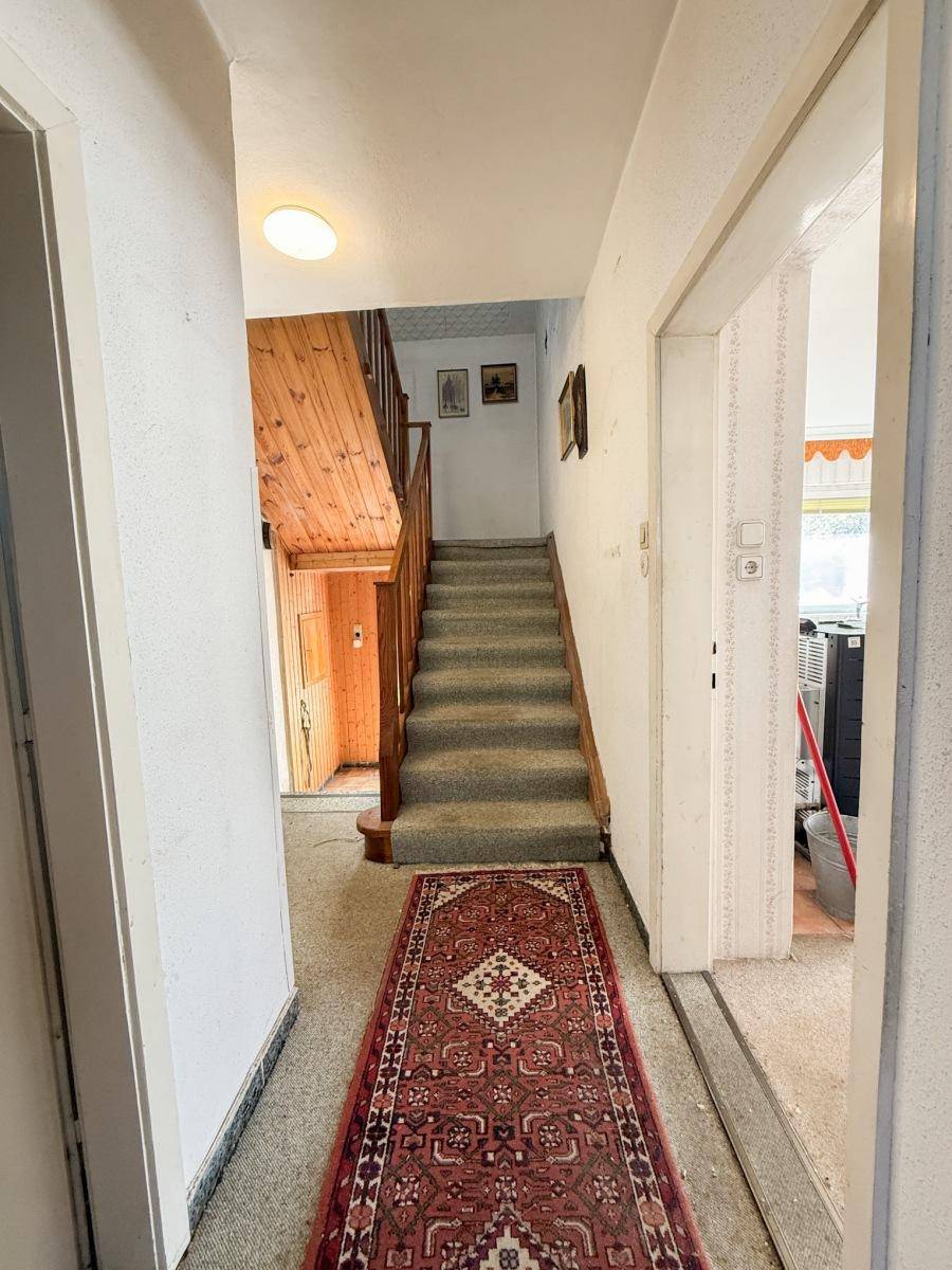 Flur mit Teppichtreppe und Holzgeländer, führt in die obere Etage.