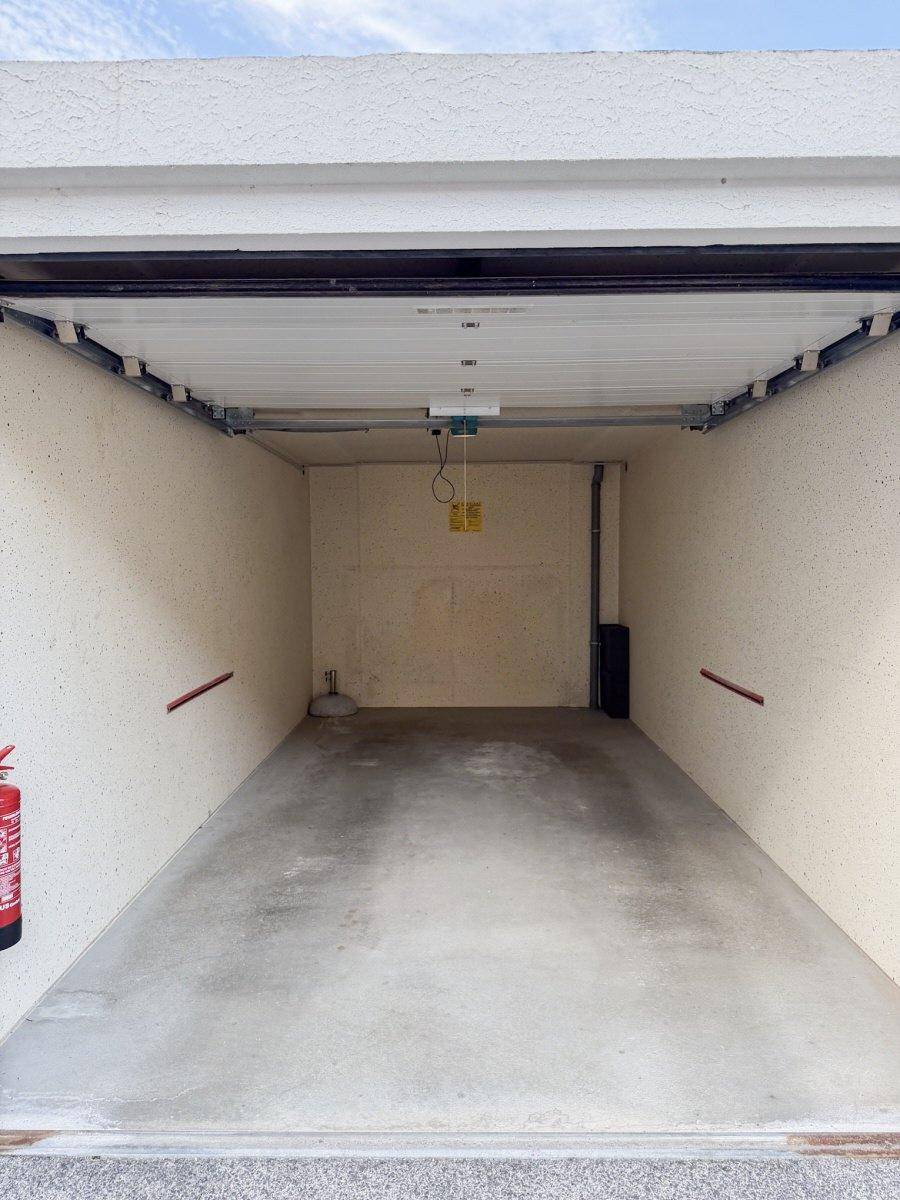Leere Einzelgarage mit Betonboden und Rolltor.
