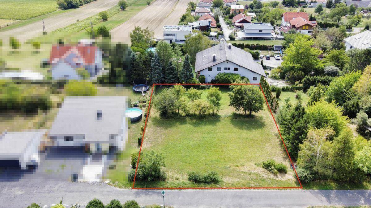 Übersicht aus der Luft eines Baugrundstücks mit roter Markierung, eingebettet in eine ländliche Umgebung.