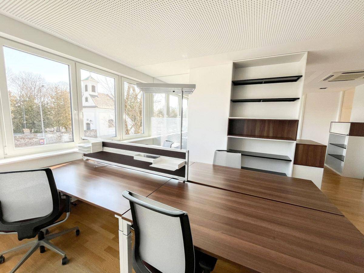Heller Büroraum mit mehreren Arbeitsplätzen, Holzfußboden und weitem Ausblick, bietet eine inspirierende Umgebung.