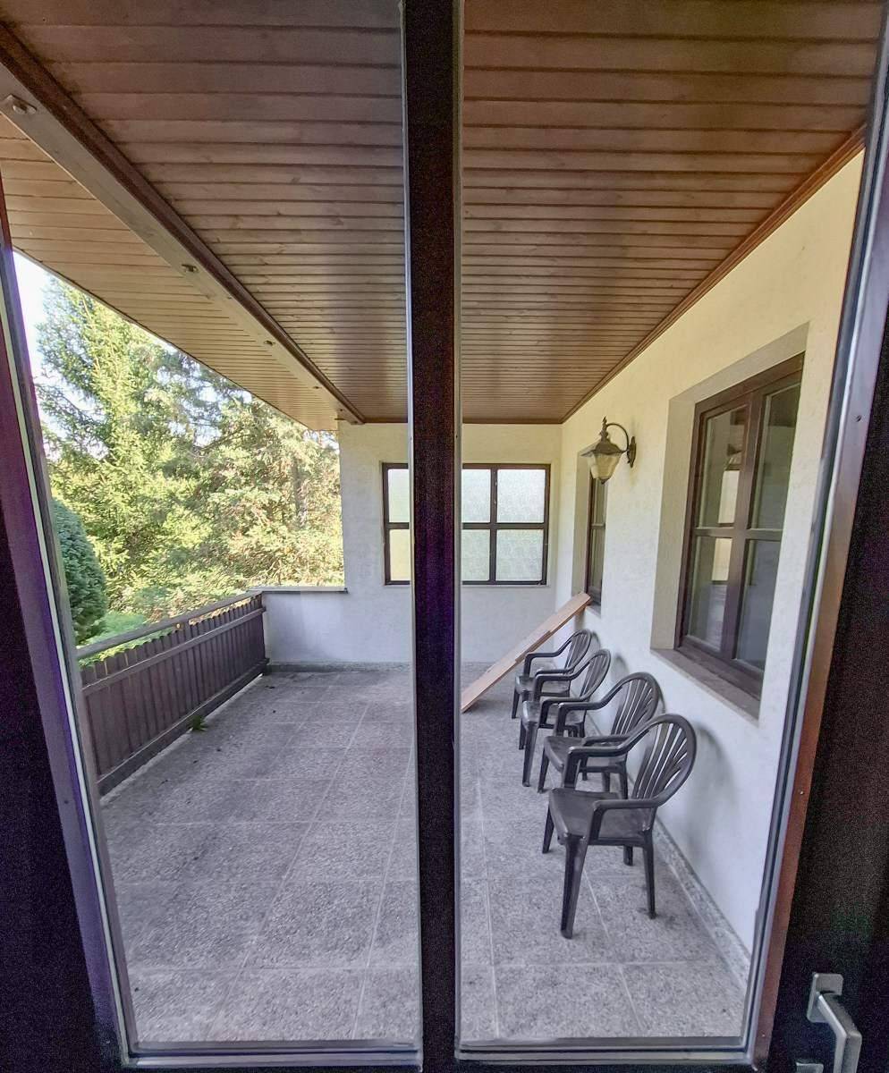 Überdachter Balkon mit Fliesenboden und einfacher Bestuhlung, ideal für entspannte Stunden im Freien.