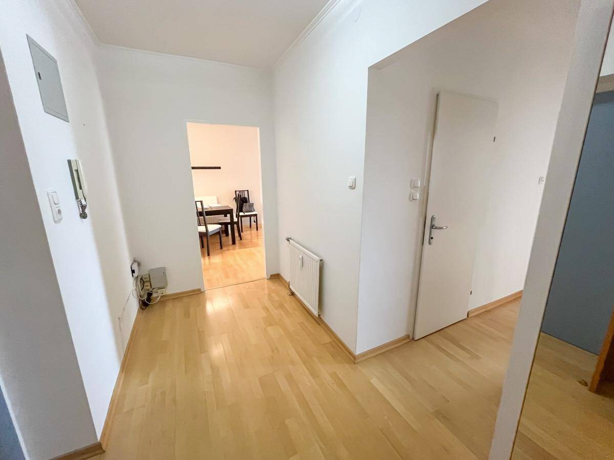 Heller Flur mit Holzfußboden, der zu den anderen Räumen der Wohnung führt.