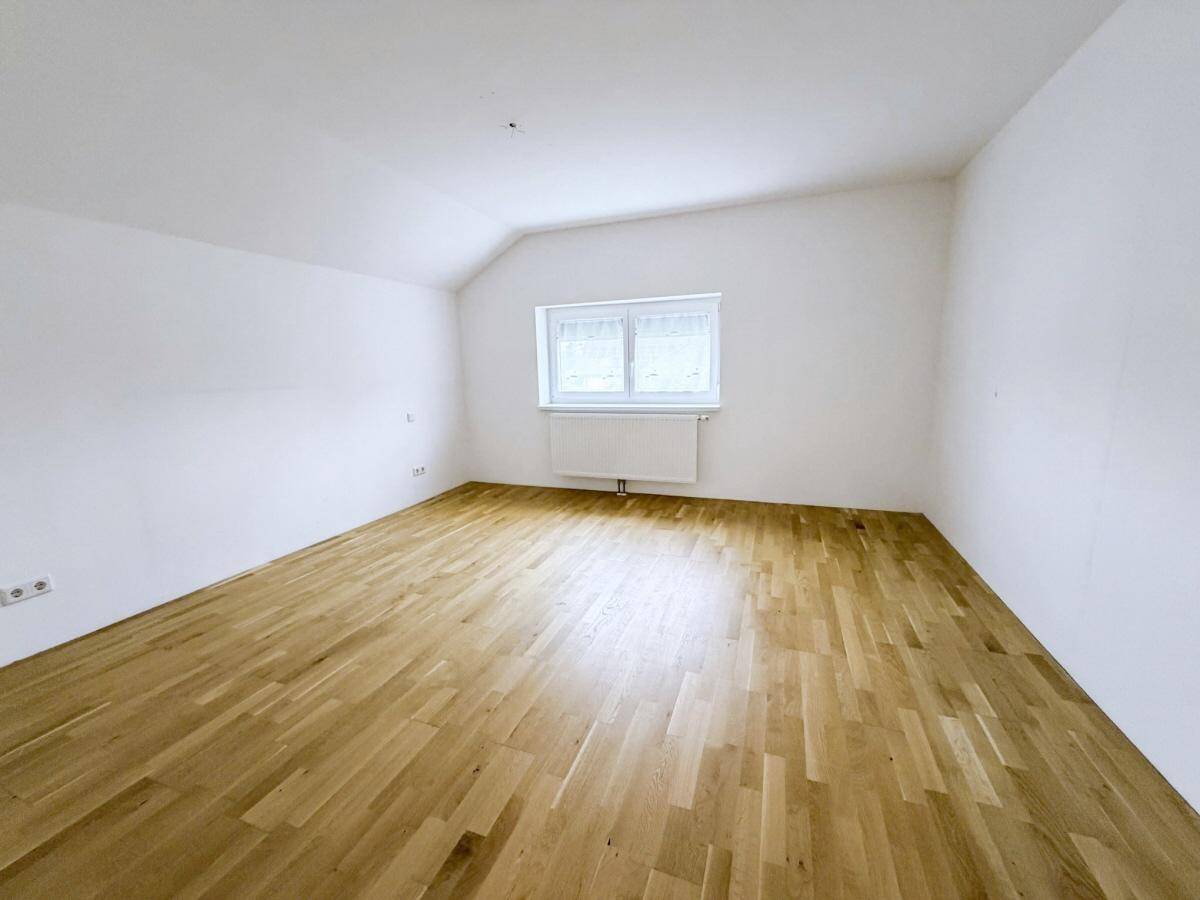 Helles Schlafzimmer mit Holzboden und Dachschräge, ideal für ein gemütliches Ambiente.