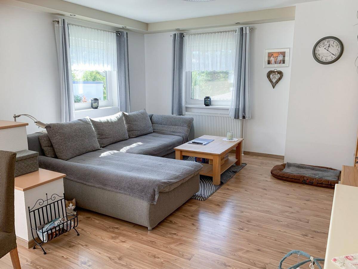 Gemütliches Wohnzimmer mit großem Ecksofa, Laminatboden und hellen Fenstern für viel Tageslicht.
