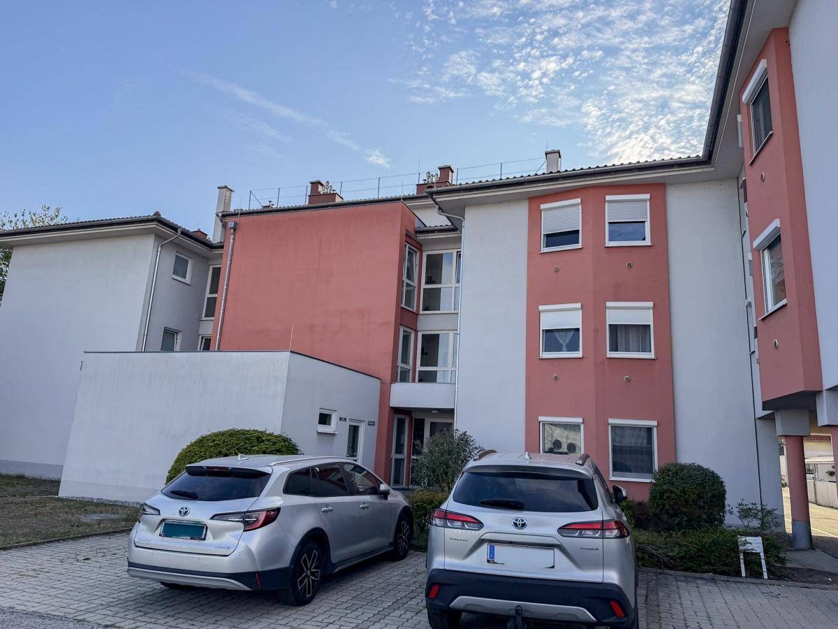Außenansicht des Mehrfamilienhauses mit Parkplätzen vor dem Gebäude.