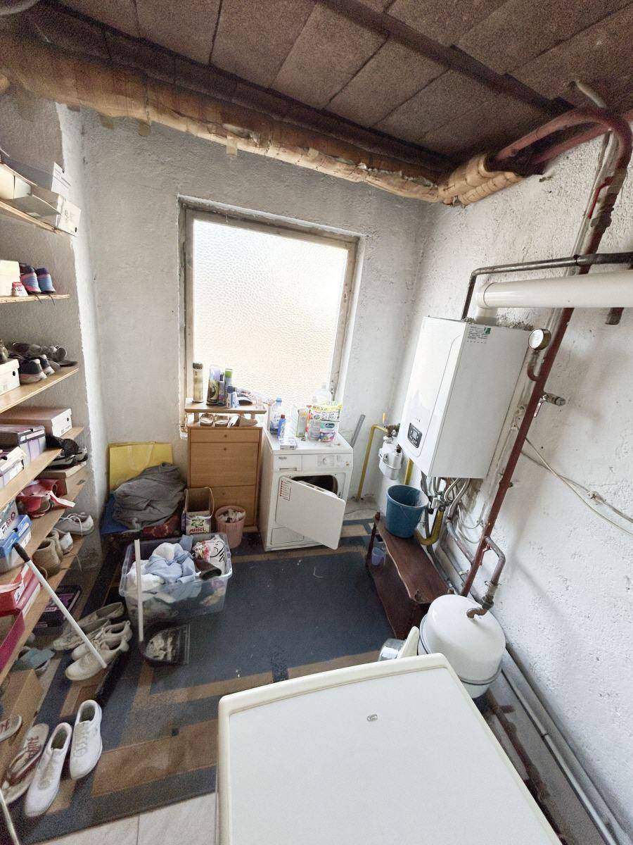 Abstellraum mit Waschmaschine, Heizungsanlage und Regalen für Lagerung.