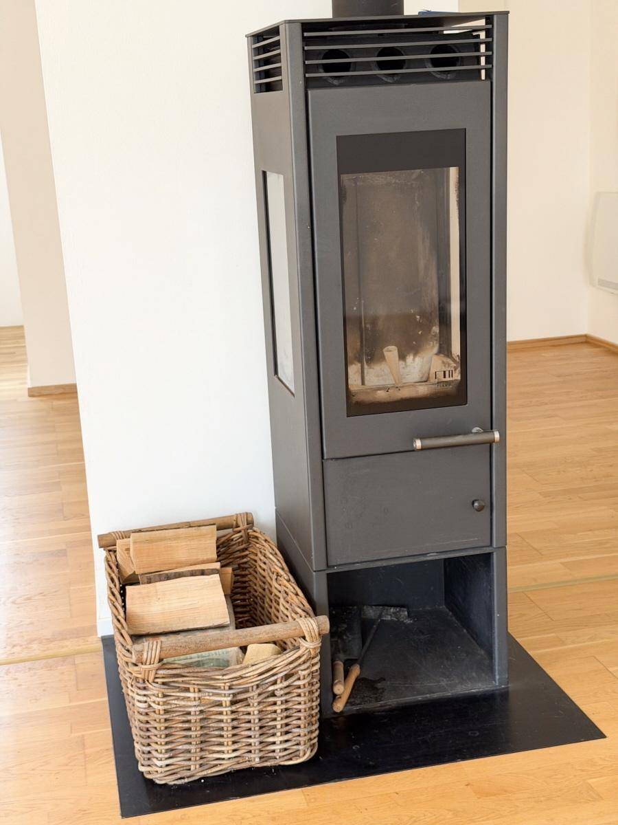 Moderner Holzofen mit Brennholzkorb, der eine gemütliche Atmosphäre schafft.