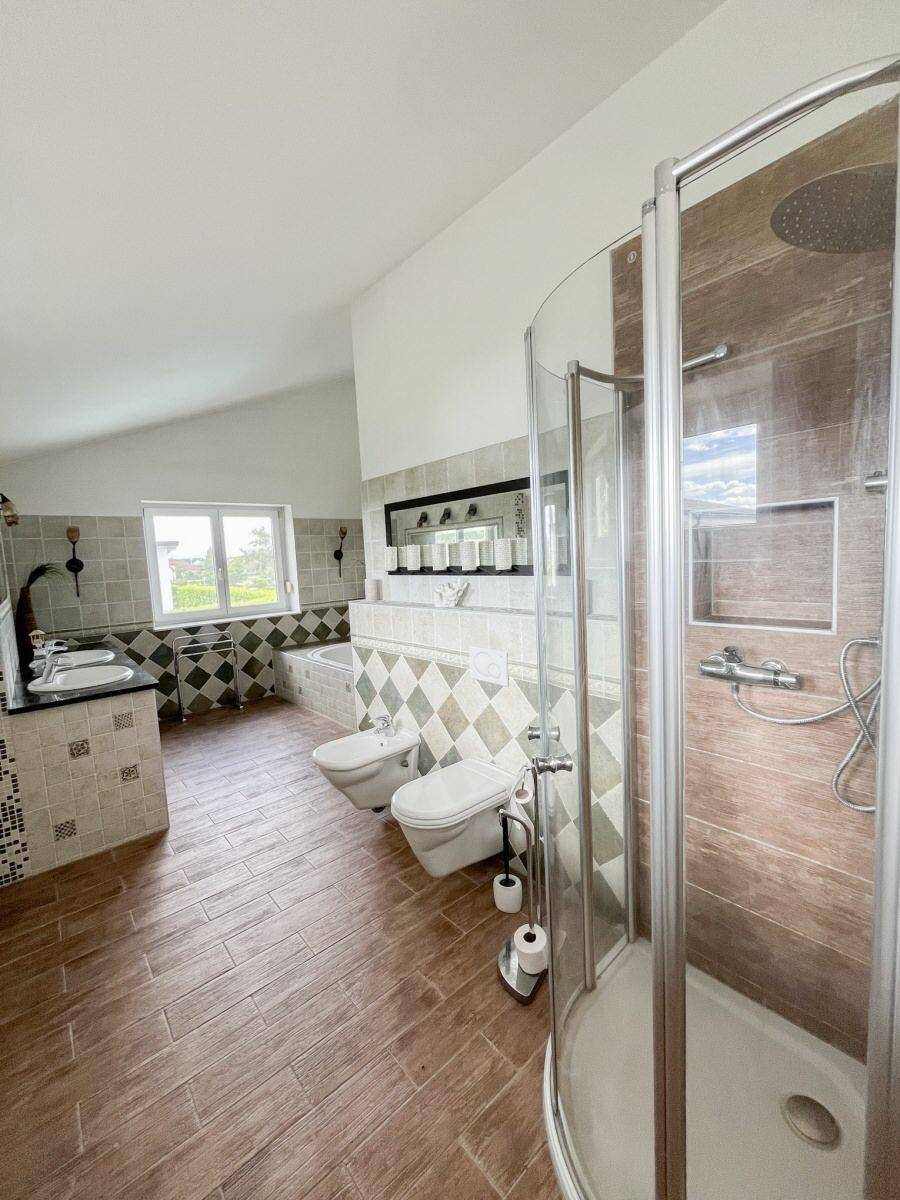 Badezimmer mit Duschkabine, Bidet und WC, passend zum Stil des Hauptbadezimmers.