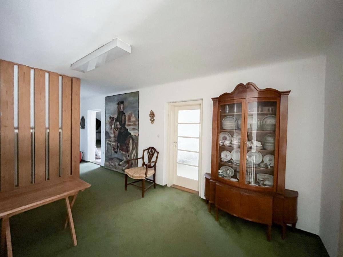 Geräumiger Flur mit grünem Teppichboden, Holzvertäfelung und einem antiken Geschirrschrank.