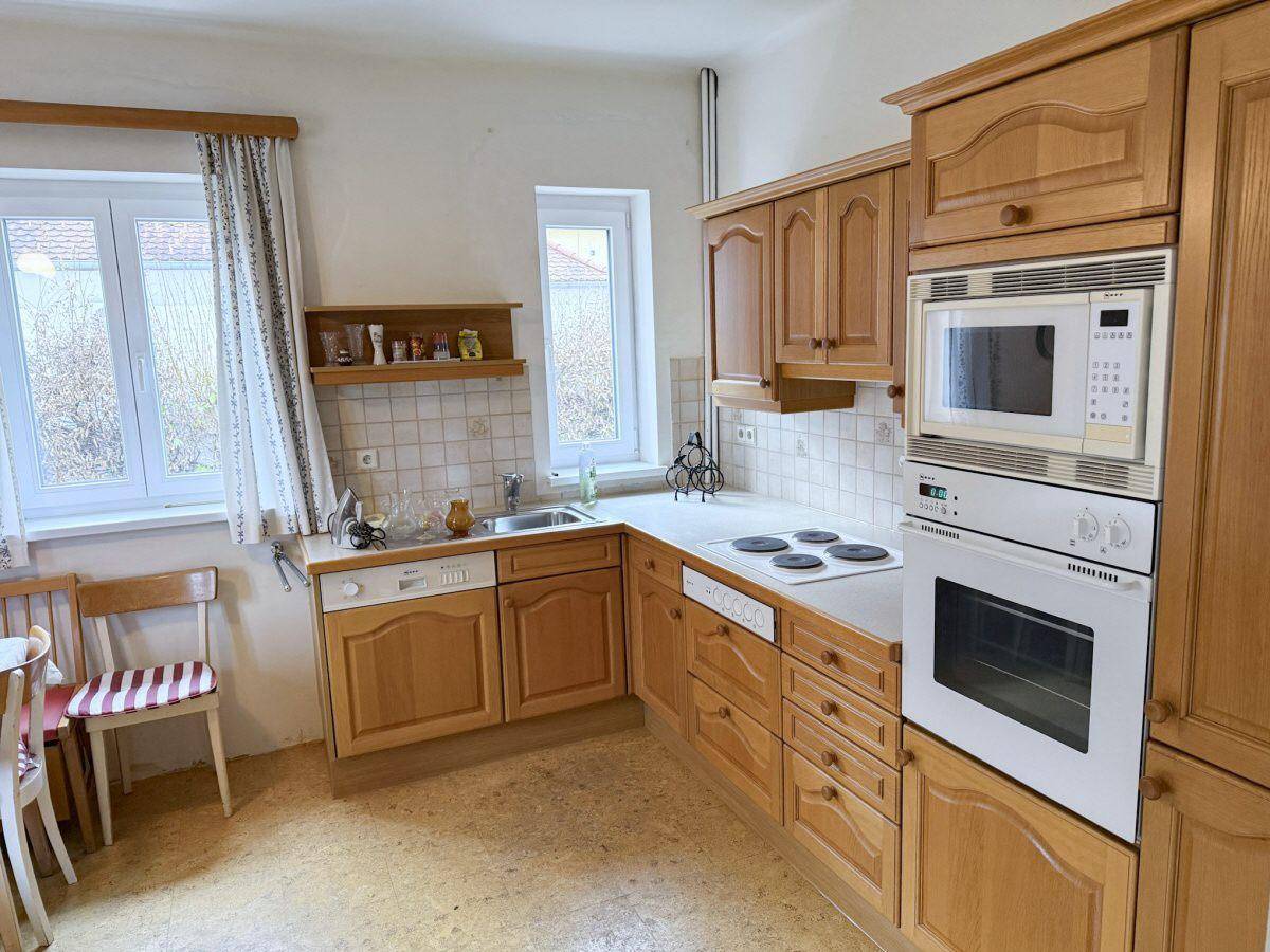 Funktionale Küche mit Holzfronten, Einbaugeräten wie Backofen und Mikrowelle sowie viel Stauraum.