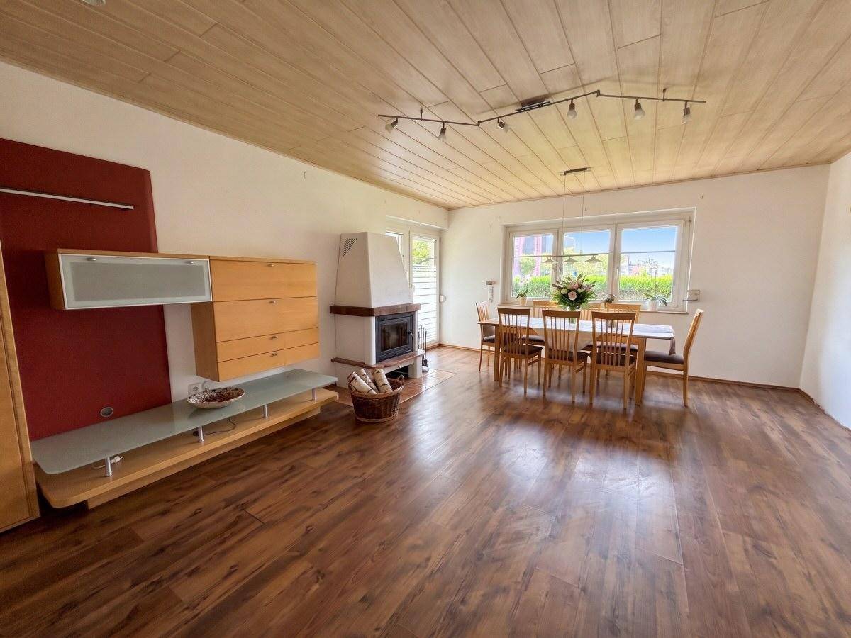 Geräumiger Wohn-Essbereich mit Holzboden, Holzdecke und Kamin für gemütliche Abende.