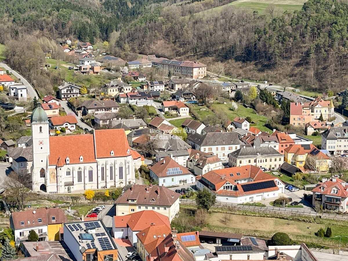 Panoramablick auf eine malerische Stadt mit Kirche und umliegenden grünen Hügeln.