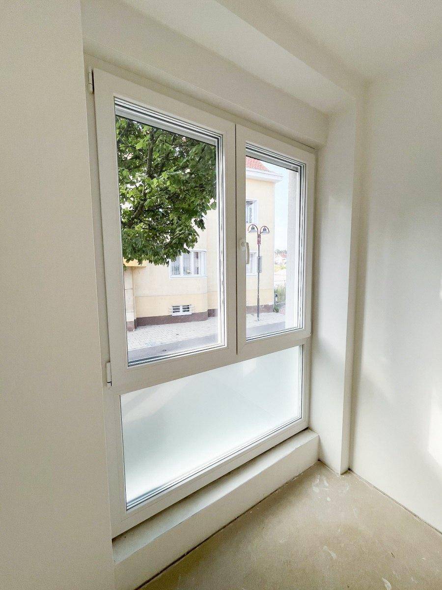 Großes Fenster mit Blick auf die Straße und umliegende Gebäude, teilweise mit Milchglas.