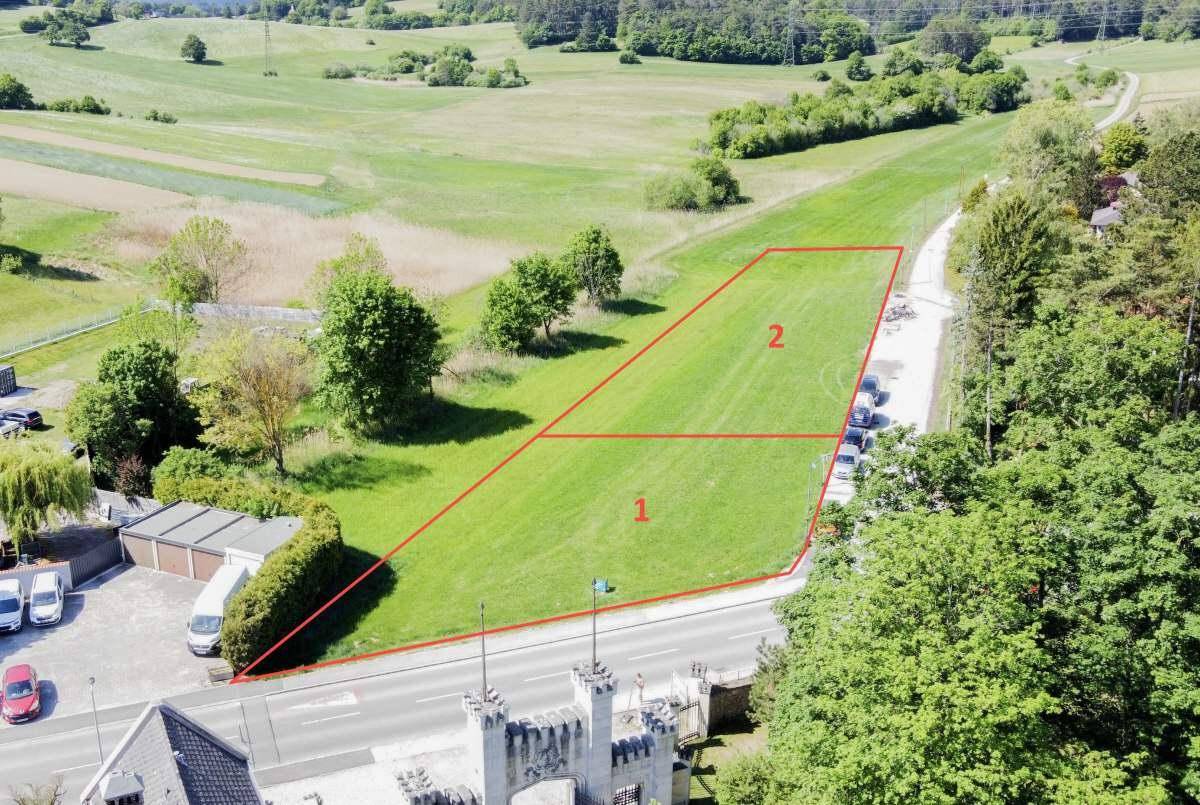 Weitläufige Luftaufnahme des Baugrundstücks mit angrenzenden Feldern und einer Straße.