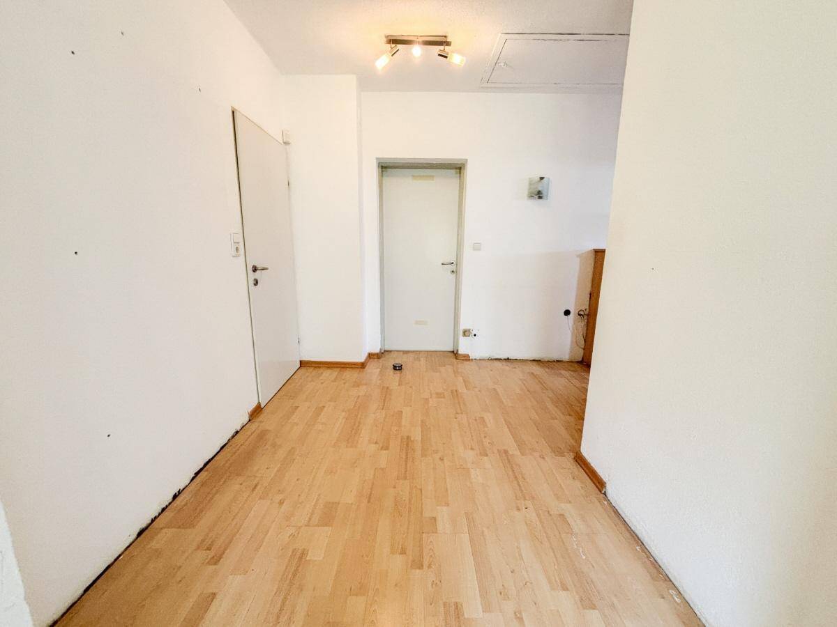 Heller Flur mit Laminatboden und weißen Wänden, bereit zur individuellen Gestaltung.