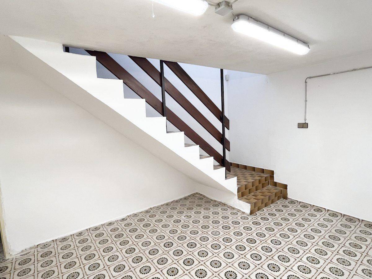 Kellerraum mit dekorativem Fliesenboden und Treppe zum Obergeschoss.