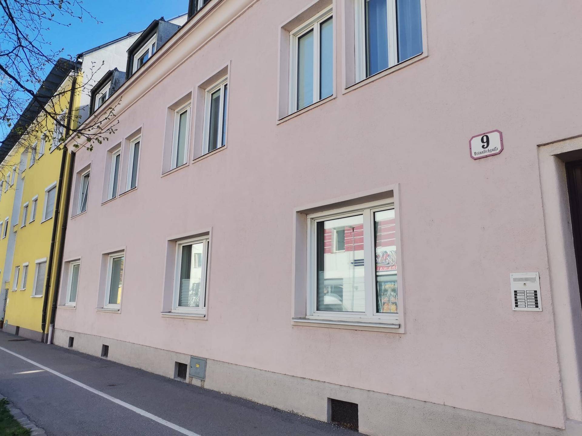 Fassade eines Mehrfamilienhauses mit mehreren Fenstern und einer Hausnummer.