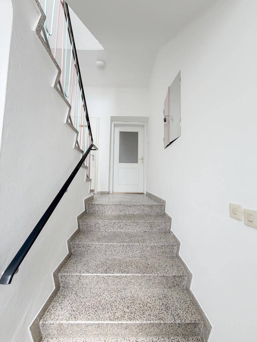 Treppenhaus mit Terrazzoboden und einem Geländer in schlichtem Design.