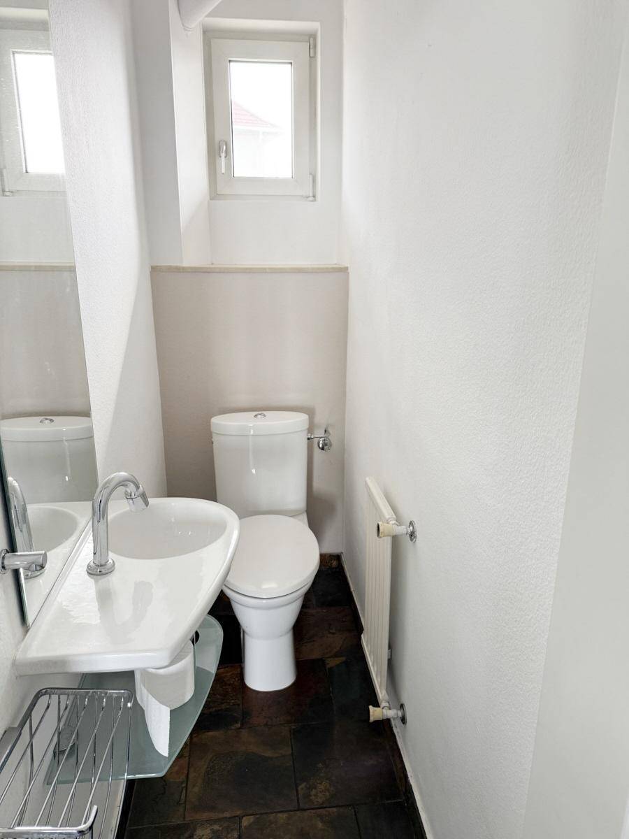 Kleines Gäste-WC mit Fenster, modernem Waschbecken und dunklem Steinboden.