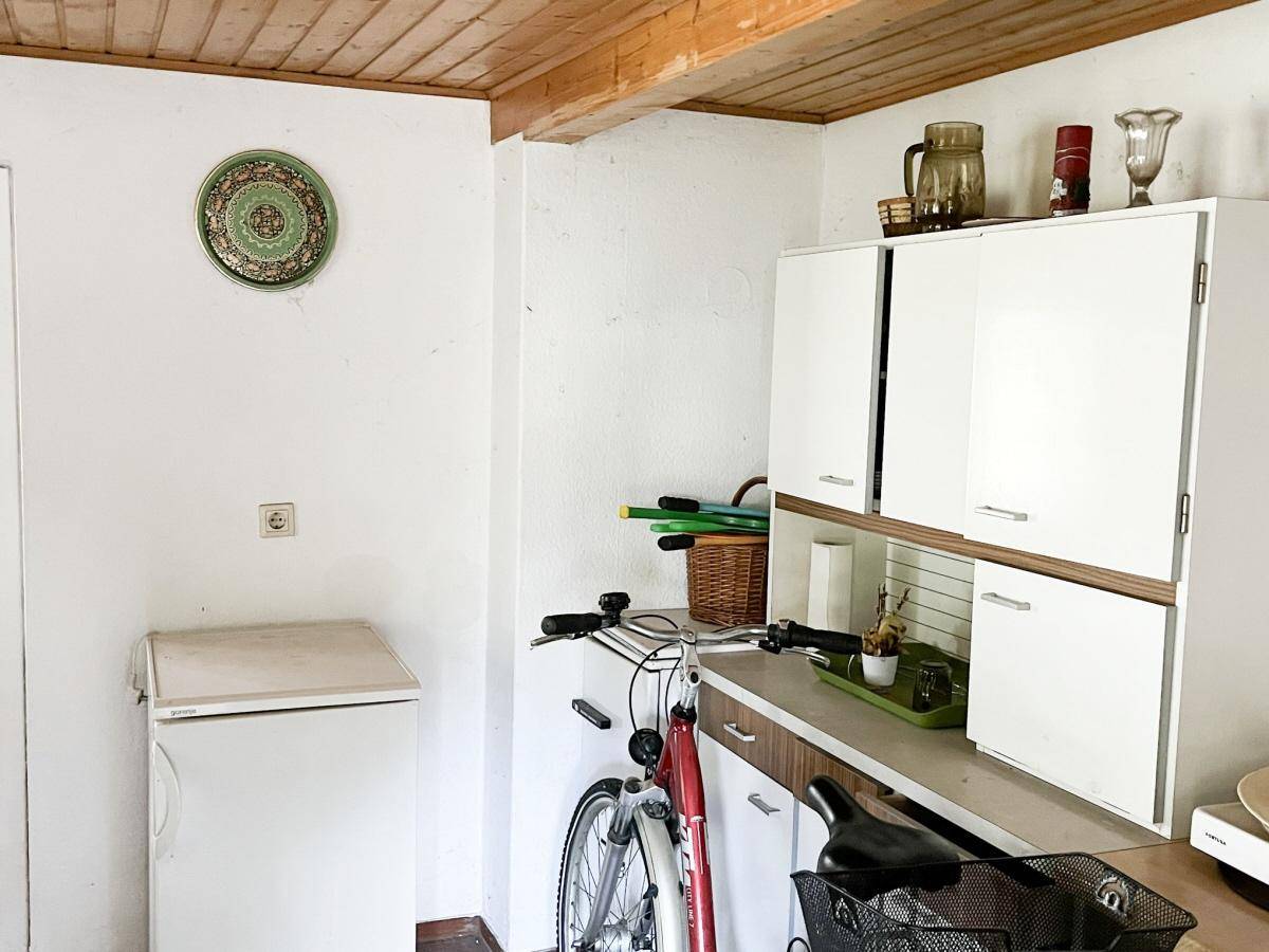 Abstellraum mit Kühlschrank, Fahrrad und Hängeschränken, ideal für zusätzlichen Stauraum.