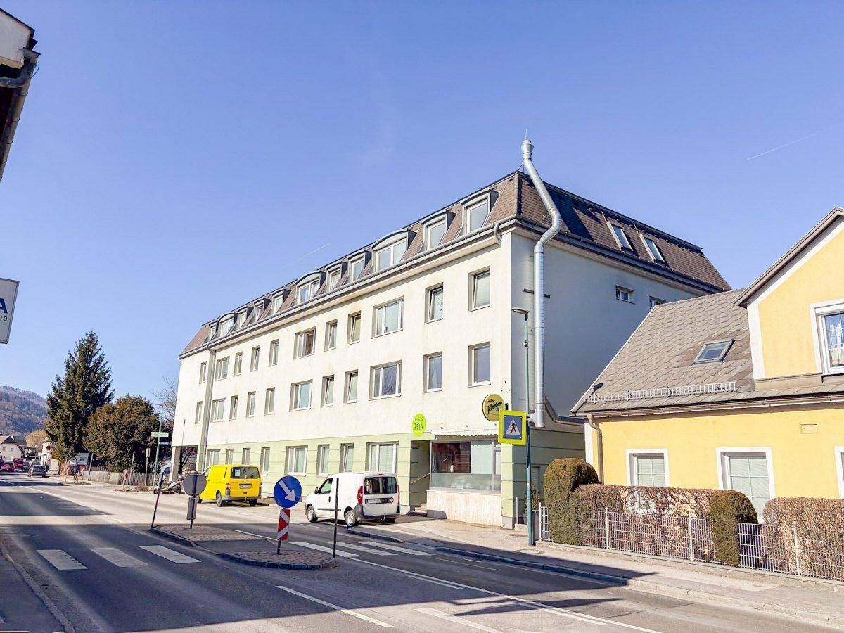 Gesamtansicht des Wohngebäudes von der Straße mit Mansarddach und umliegender Bebauung.