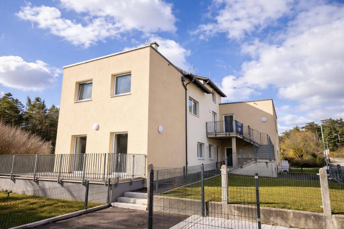 Moderne Fassade eines Neubaus mit Balkonen und Zugang zum Gebäude.