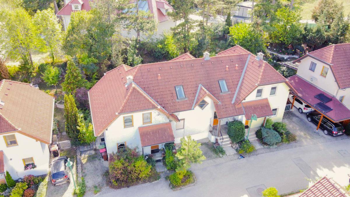 Übersicht der Reihenhäuser von oben mit roten Dächern und grüner Umgebung.