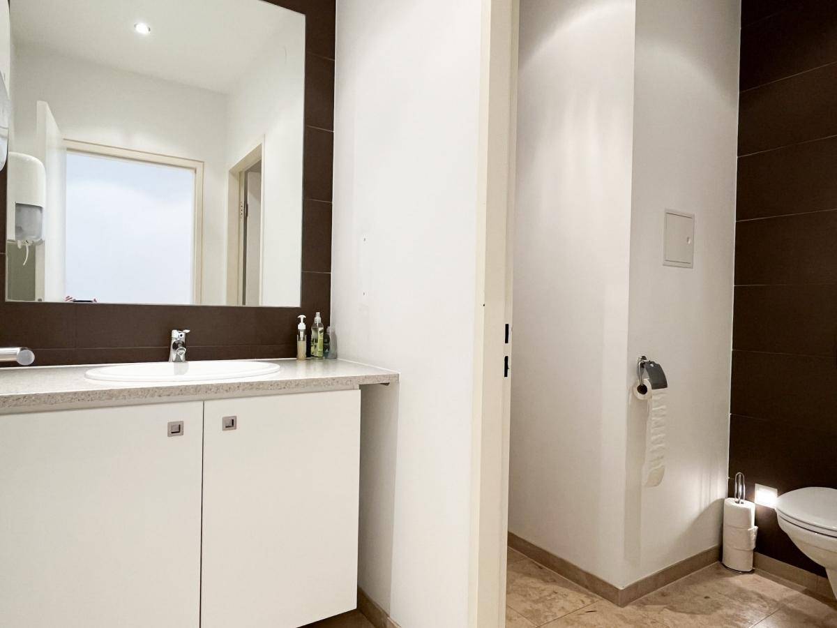 Helles Badezimmer mit Waschtisch, großem Spiegel und braunen Wandfliesen, bietet Komfort und Funktionalität.