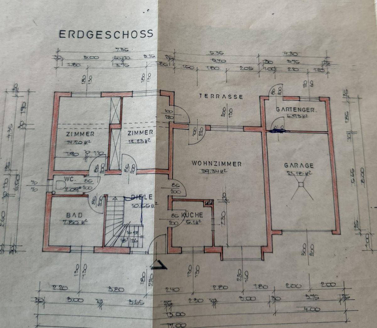 Grundriss des Erdgeschosses mit großem Wohnzimmer, separater Küche, zwei weiteren Zimmern, Bad, WC, Garage und Terrasse.