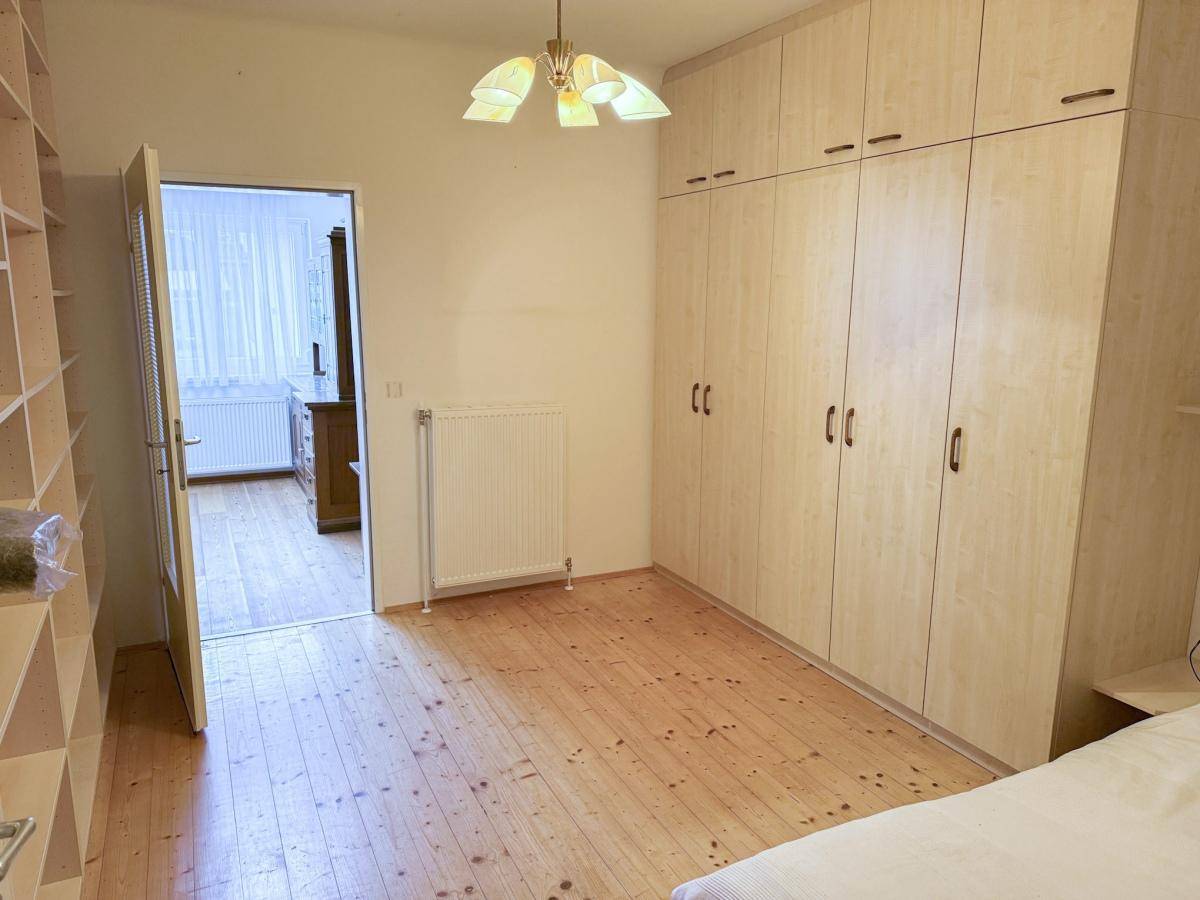 Helles Schlafzimmer mit Holzboden, großem Einbauschrank und Zugang zu einem weiteren Raum.