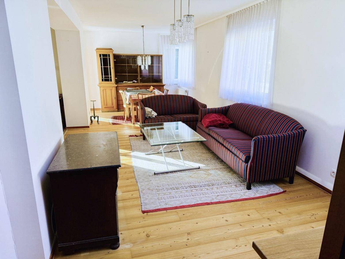Geräumiger Wohn- und Essbereich mit Holzboden, bequemen Sofas und einem Esstisch im Hintergrund.