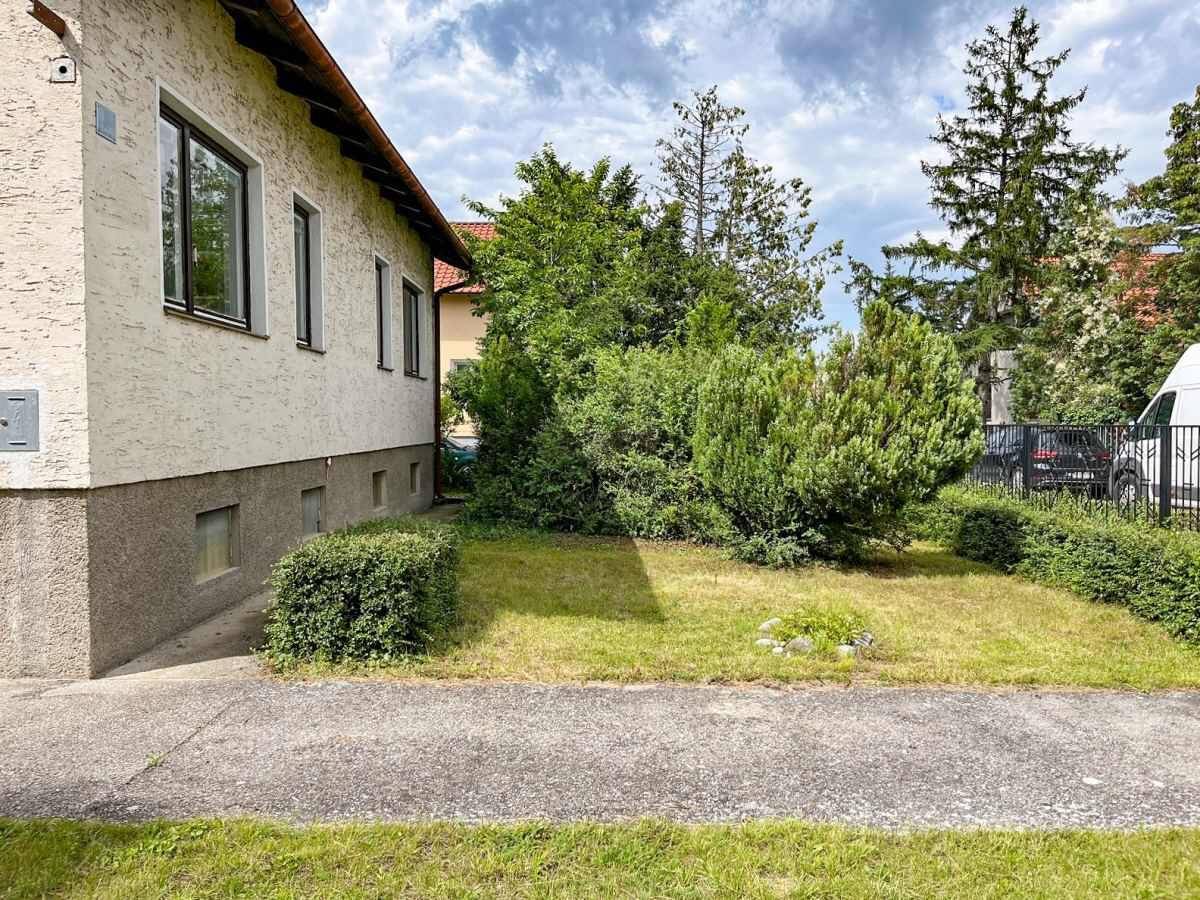 Seitenansicht des Hauses mit gepflegtem Vorgarten und Sträuchern.