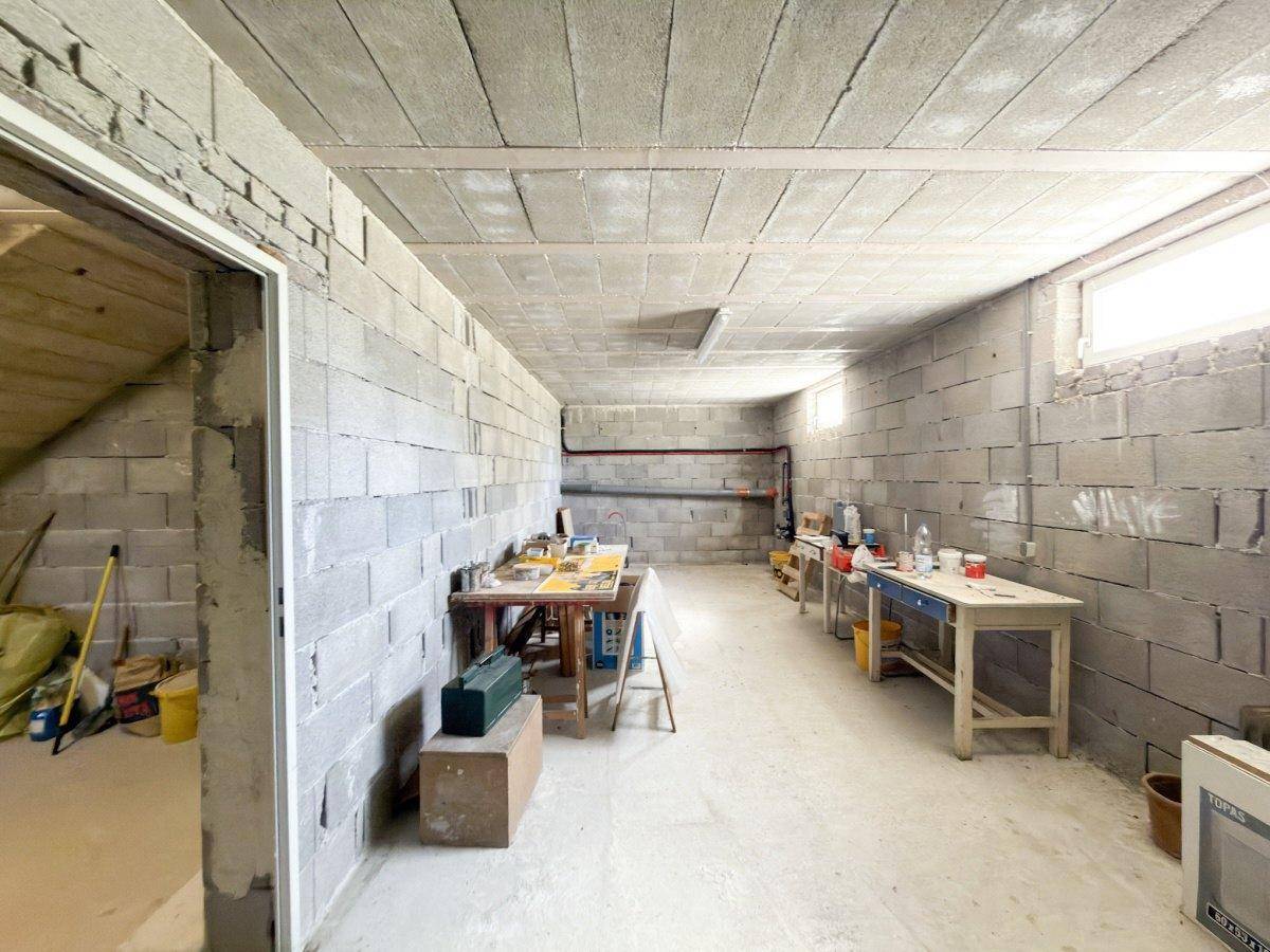 Geräumiger Kellerraum, ideal als Werkstatt, mit Betonwänden und Fenstern.