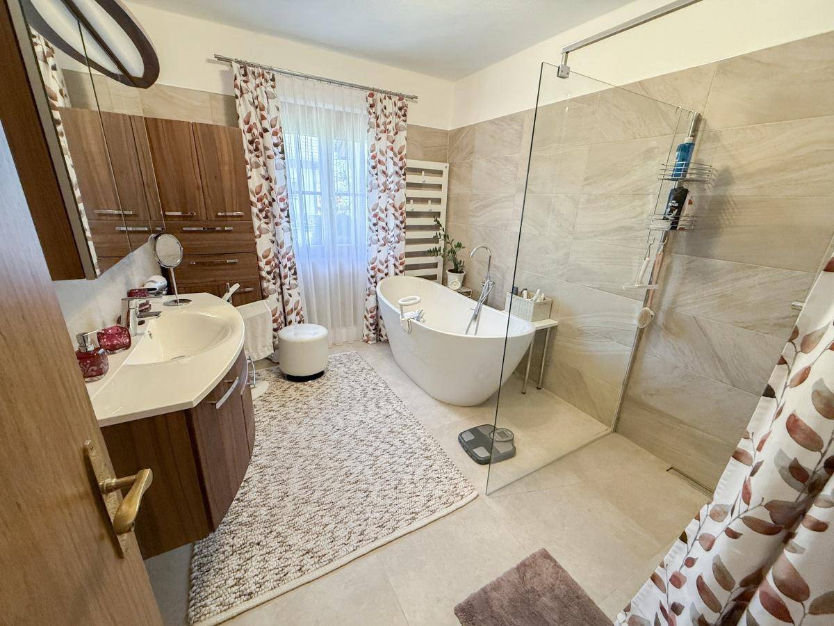 Modernes Badezimmer mit freistehender Badewanne, großer Dusche und Holzschränken.