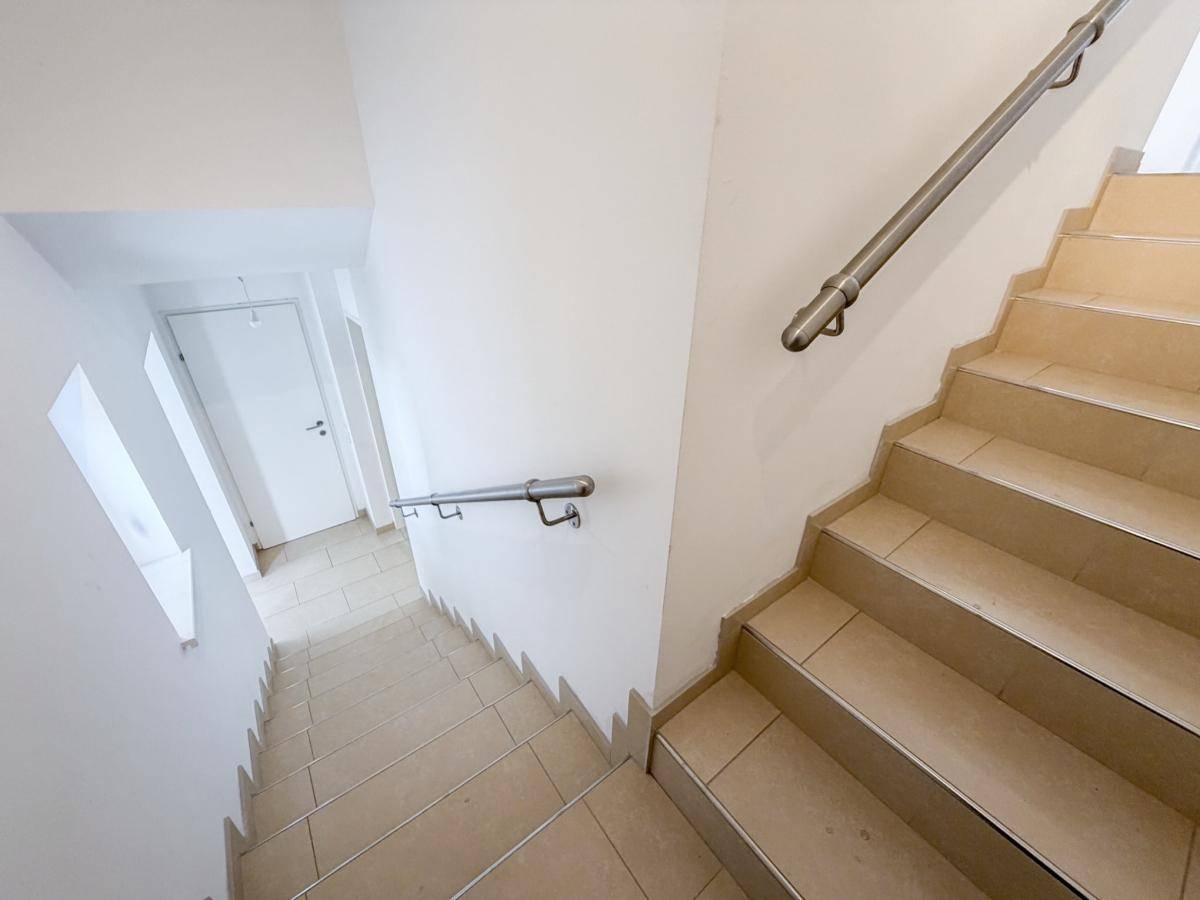 Treppenhaus mit Fliesenboden und Handläufen, das die verschiedenen Etagen verbindet.