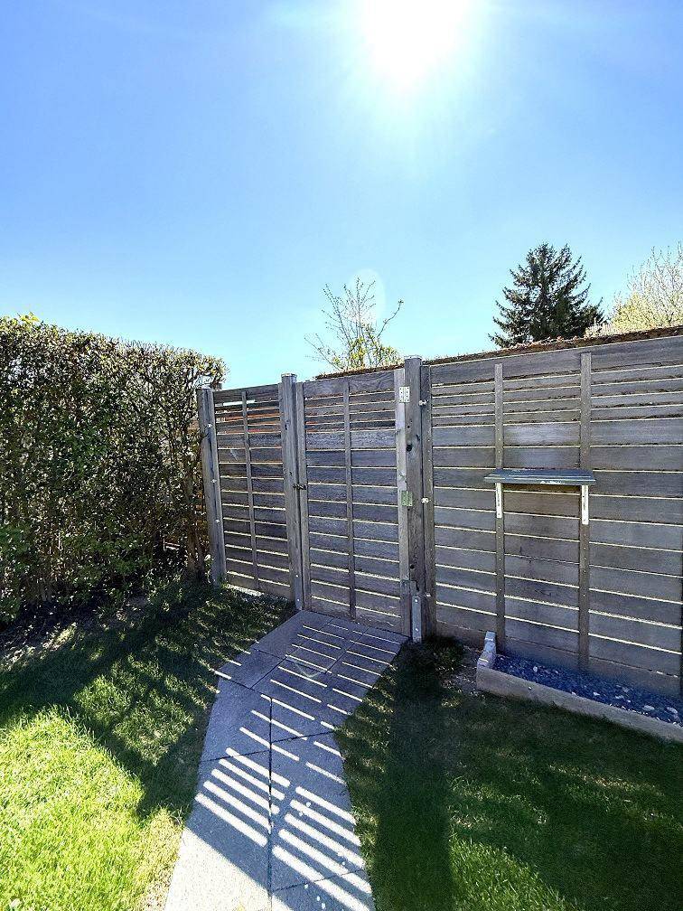 Holztor im Garten, umgeben von einer hohen Hecke, bietet Zugang zum Grundstück.