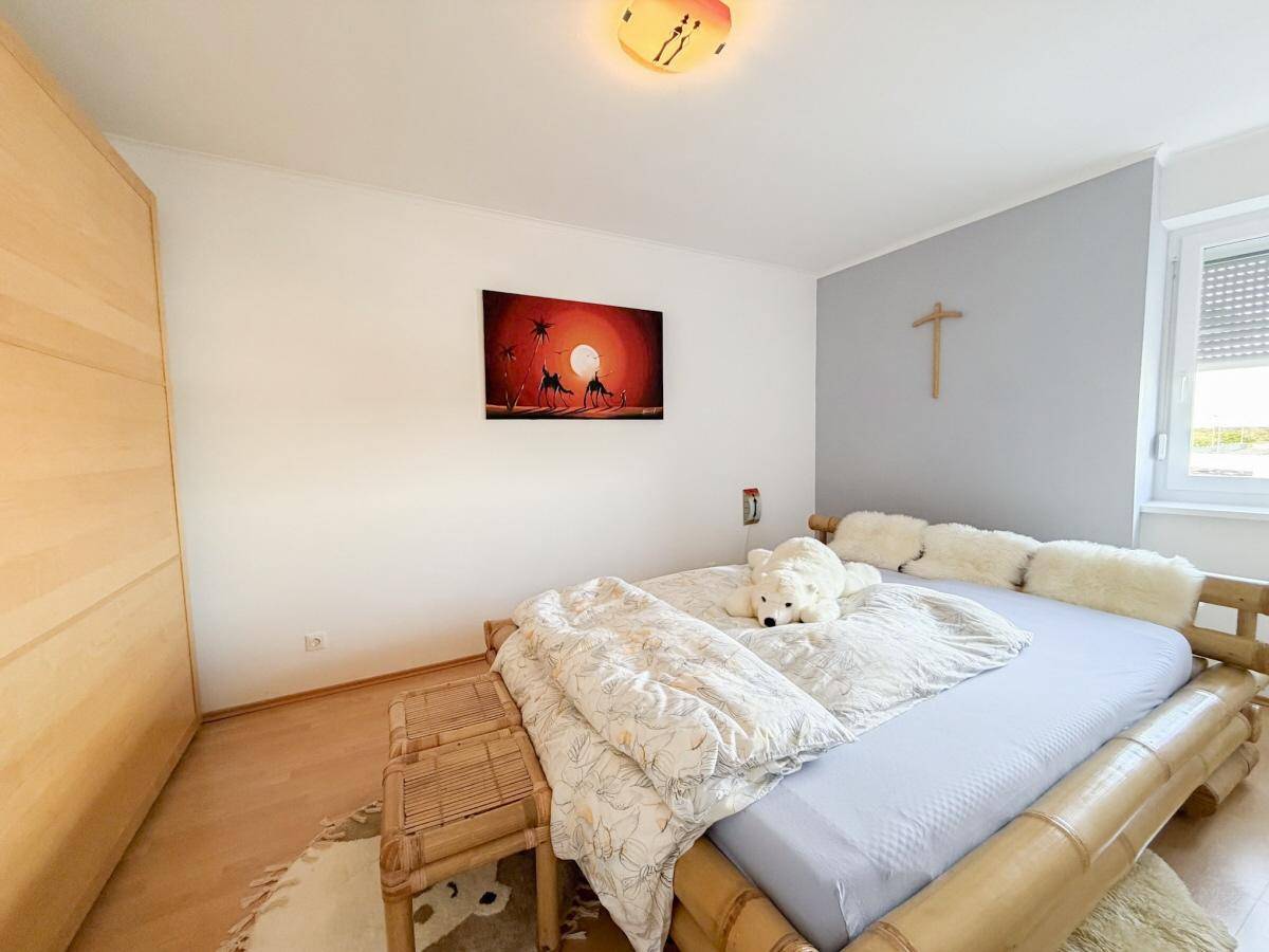 Gemütliches Schlafzimmer mit Bambusbett, Holzschrank und hellem Holzboden.
