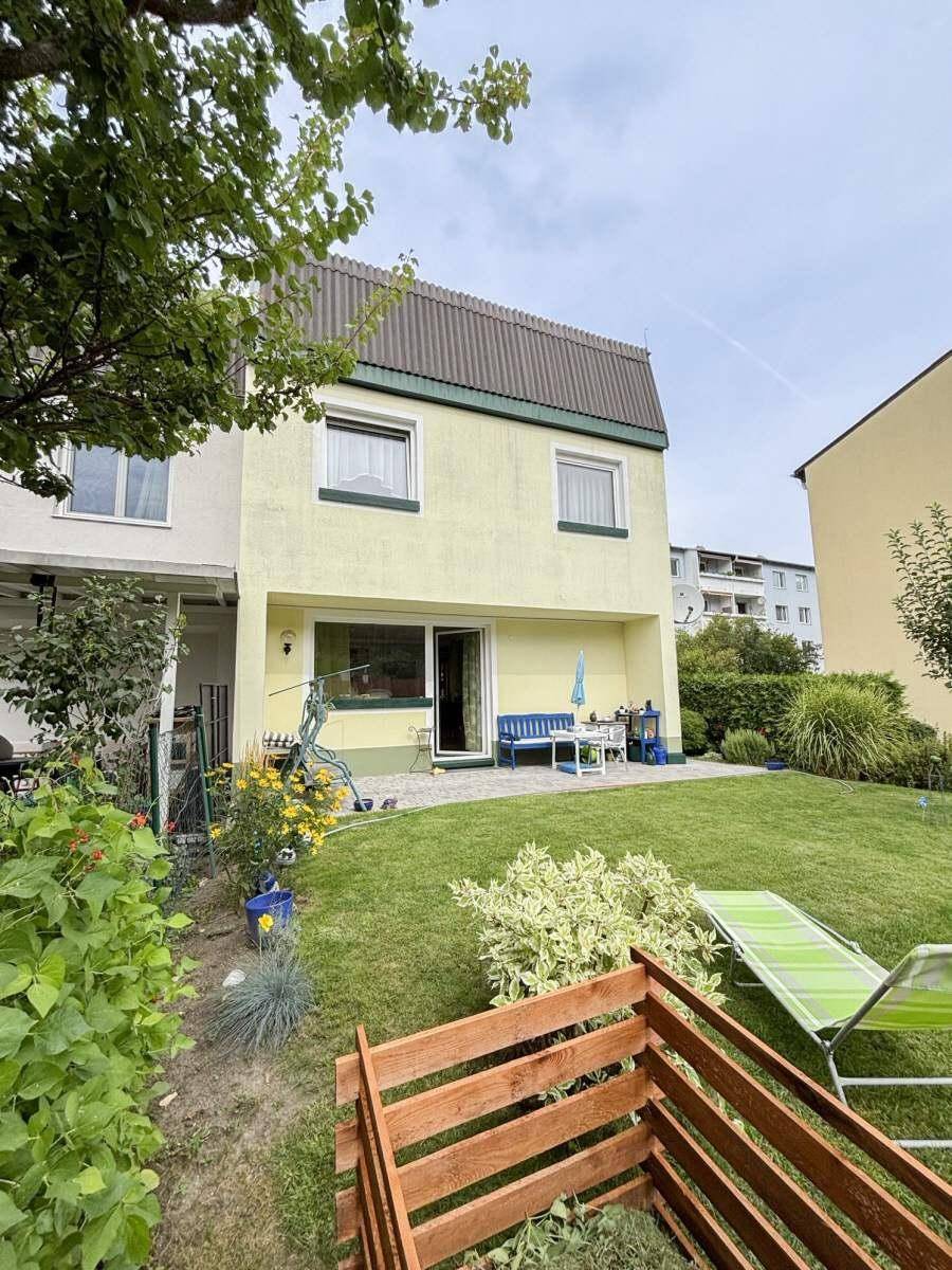 Ansicht des Hauses vom Garten aus mit Rasenfläche und einem Kompostbehälter im Vordergrund.