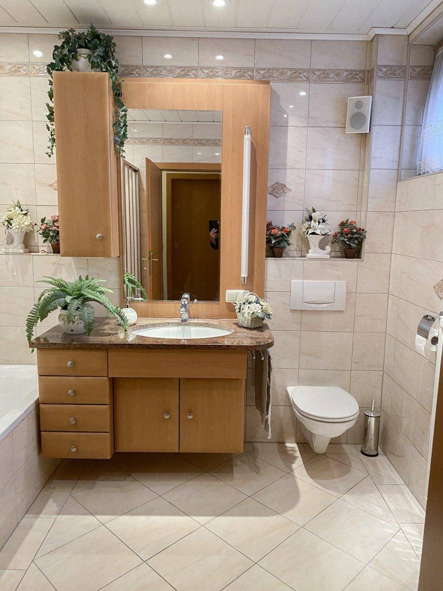 Gefliestes Badezimmer mit Waschtisch, Toilette und Spiegelschrank.