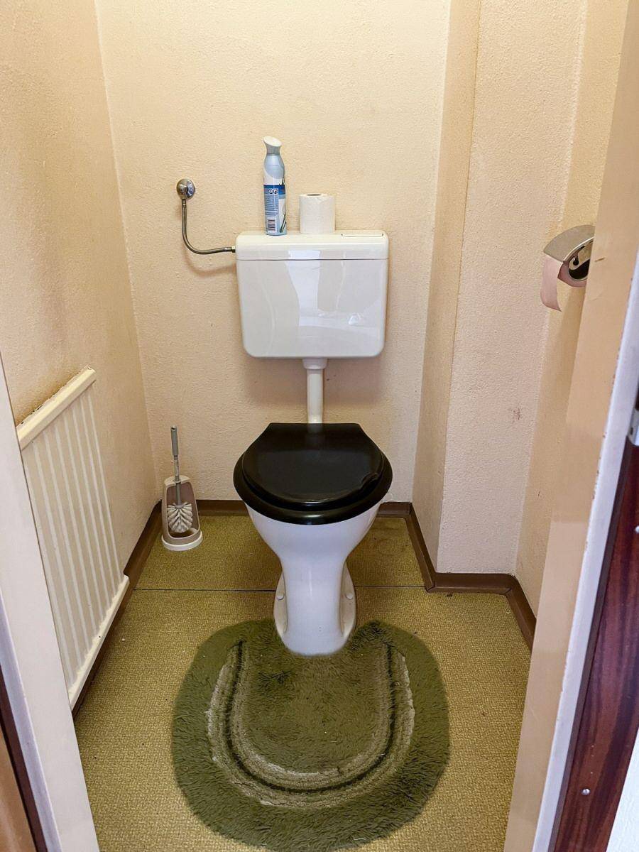 Kleines Gäste-WC mit Toilette und Teppichboden, funktional und einfach gehalten.