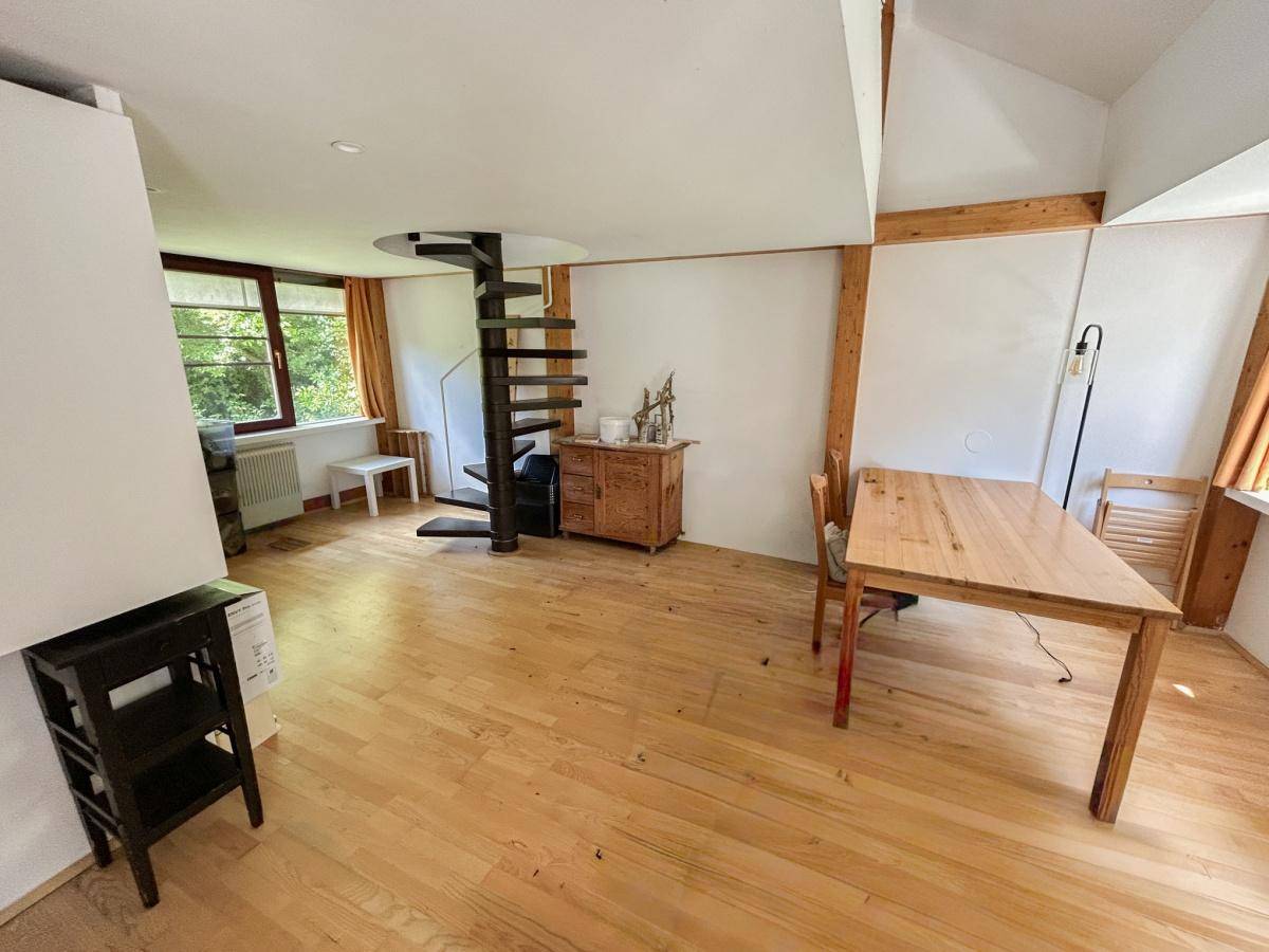 Essbereich mit hellem Holzfußboden, Esstisch und einer eleganten Wendeltreppe.