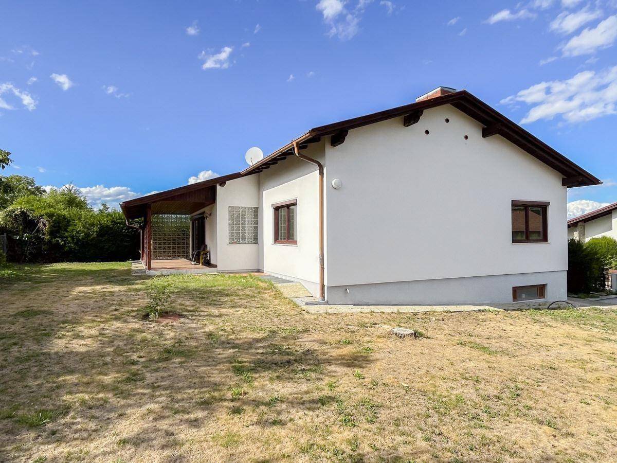 Ansicht des Hauses von der Gartenseite mit Rasenfläche und überdachter Terrasse.