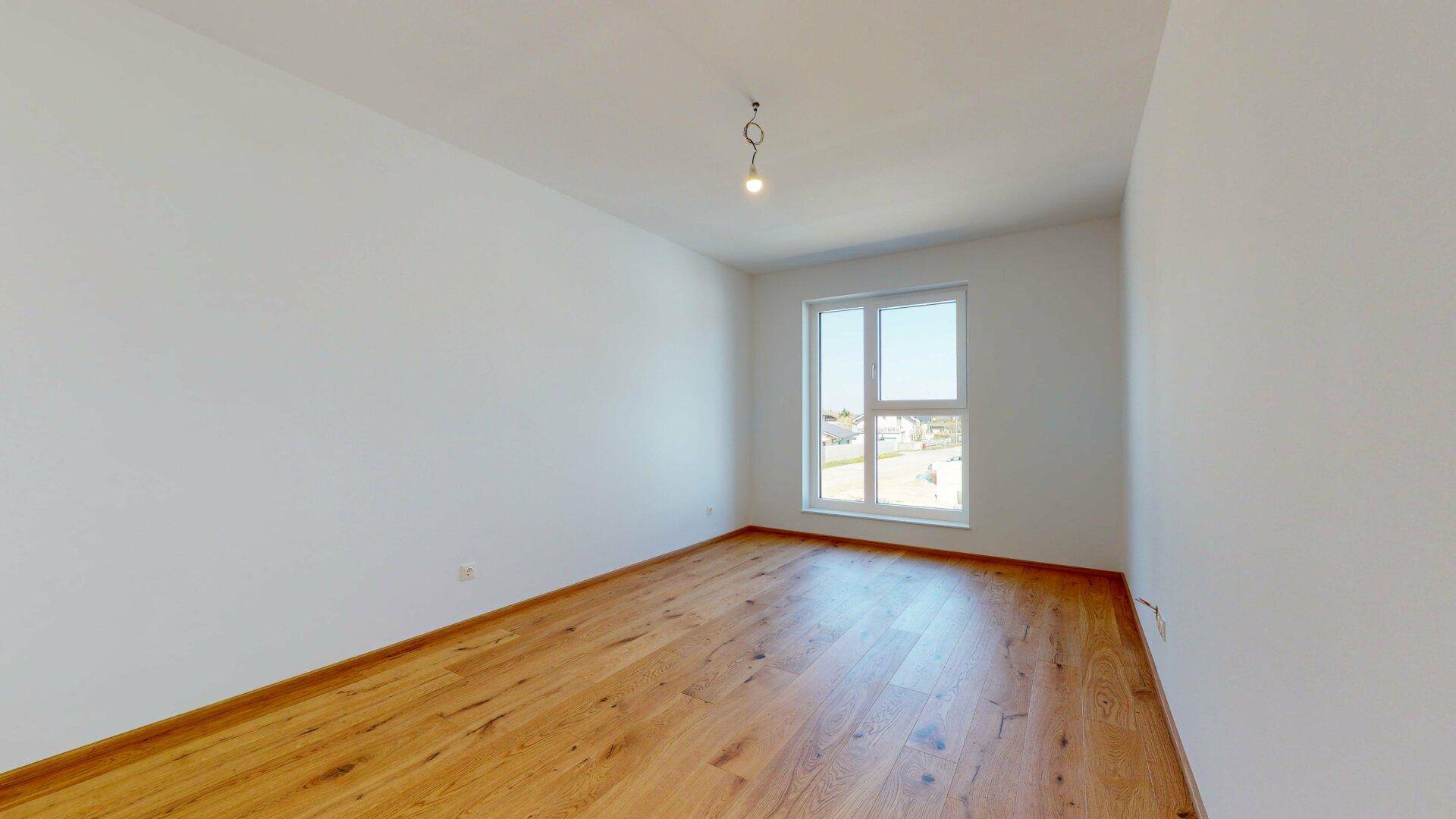 Helles Schlafzimmer mit Holzboden und großem Fenster, bietet viel Tageslicht.