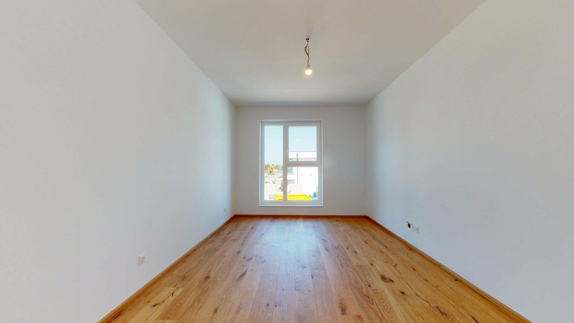 Heller, leerer Raum mit großen Fenstern und schönem Holzboden, bereit zur individuellen Gestaltung.