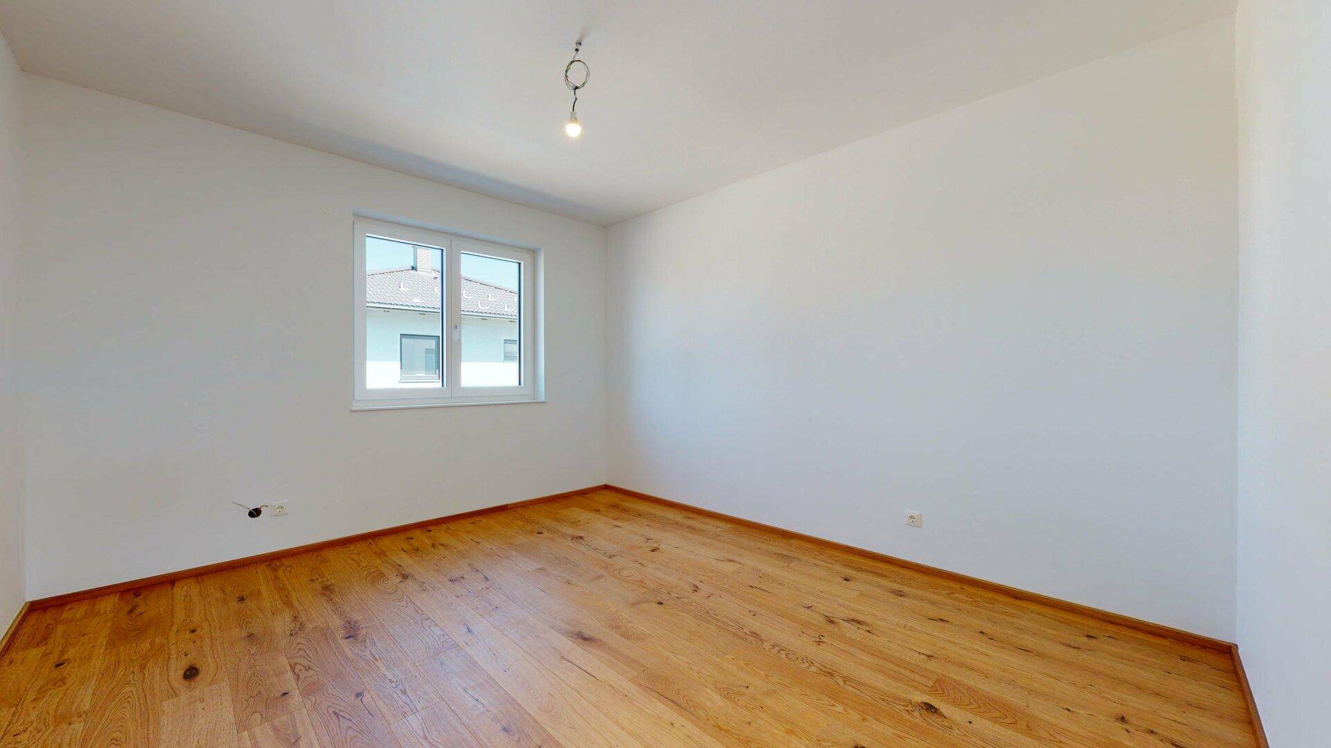 Helles Zimmer mit Holzboden und Fenster, ideal als Schlaf- oder Arbeitszimmer.