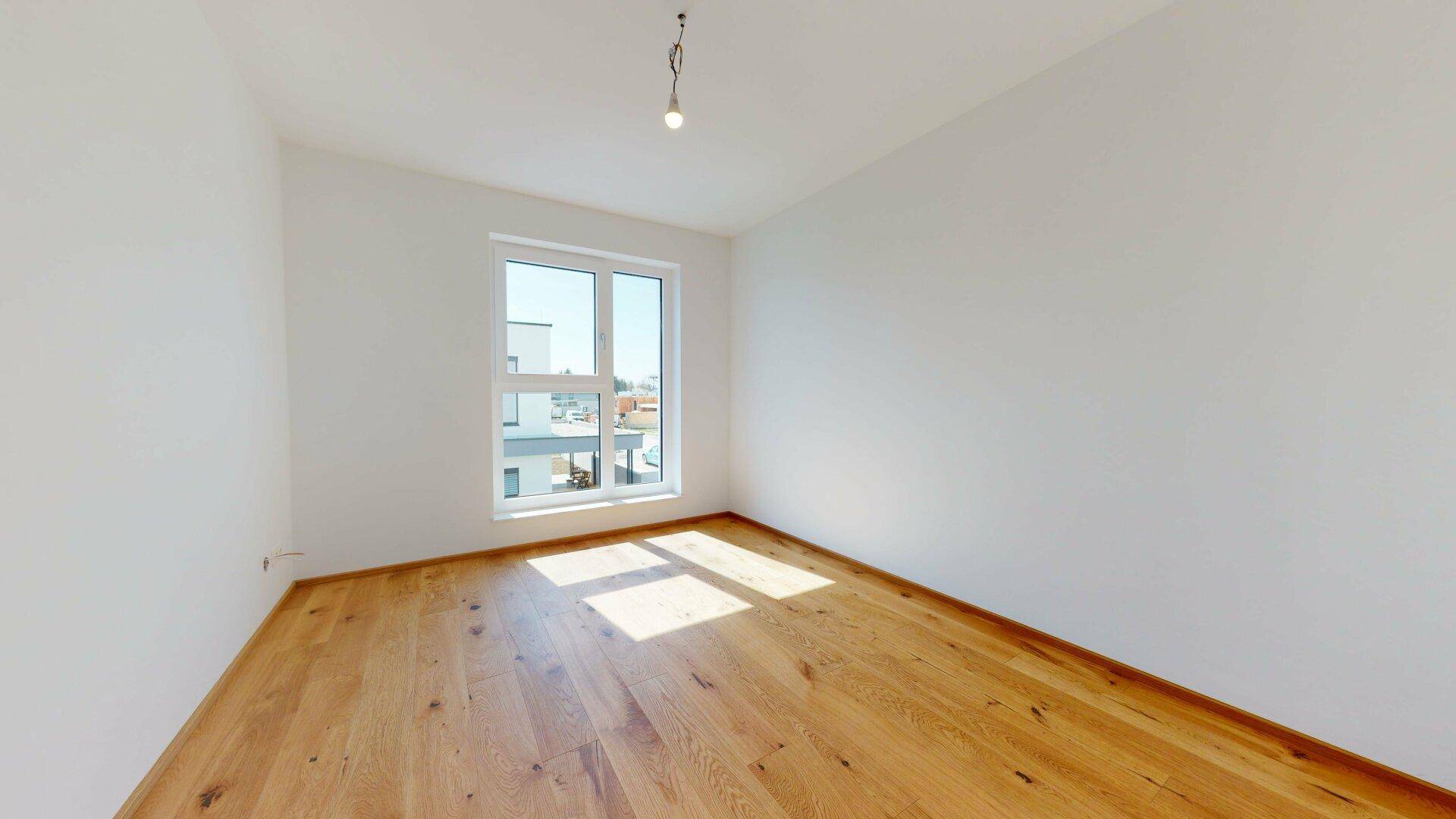 Sonnendurchfluteter Raum mit hellem Holzboden und großem Fenster, ideal für viel Tageslicht.