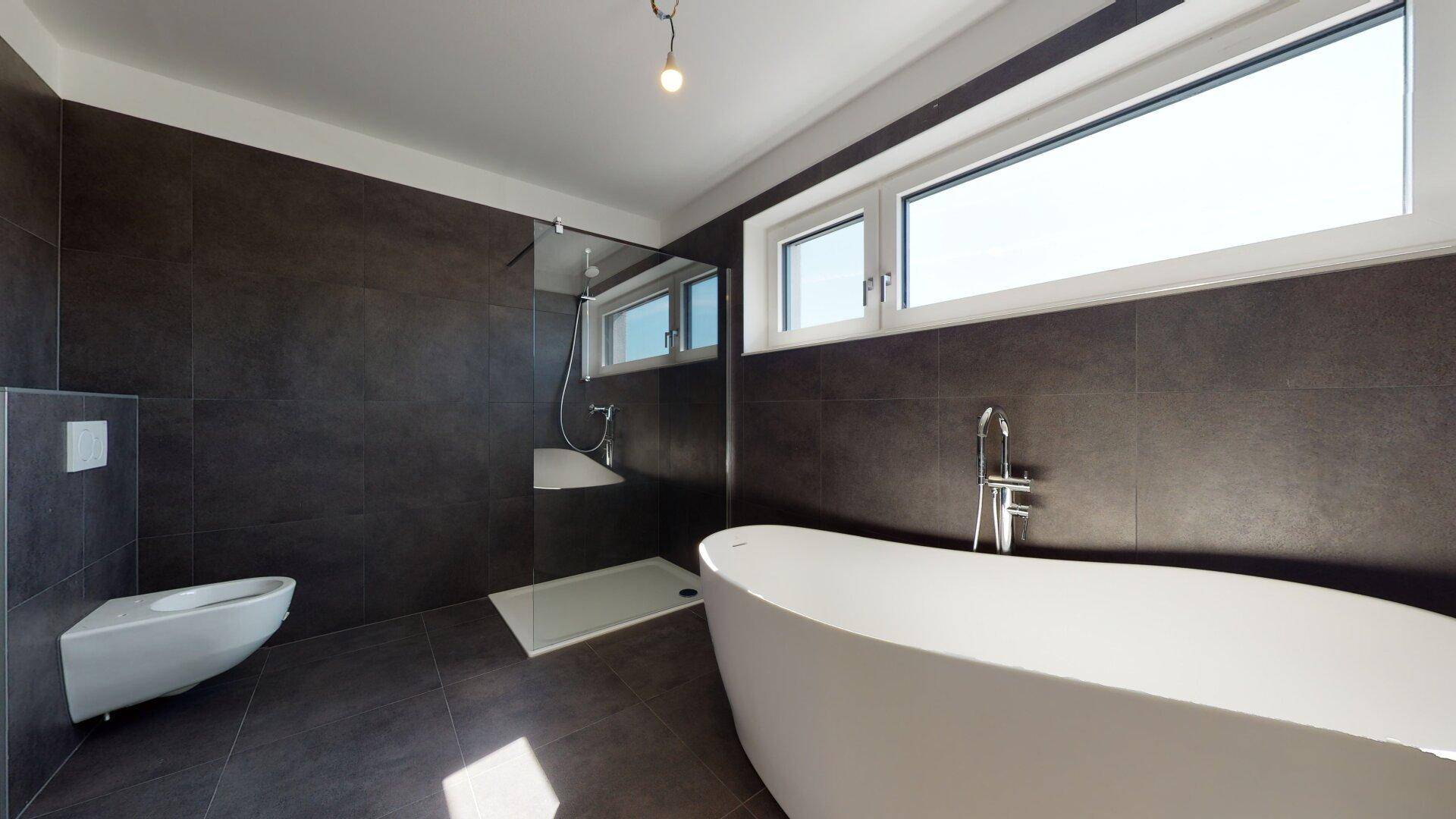 Geräumiges Badezimmer mit moderner freistehender Badewanne, Dusche und Wand-WC.
