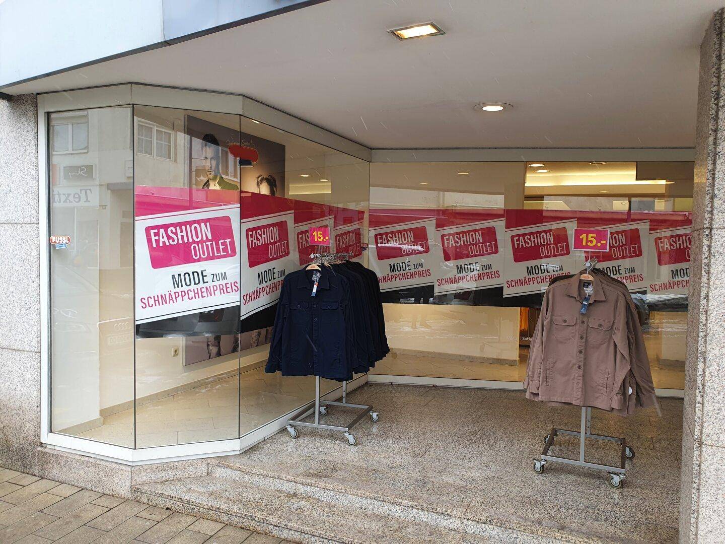 Schaufenster eines Ladens mit Auslagen und Werbehinweisen für einen Fashion Outlet.